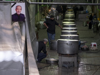 An Iranian man is standing next to the large pots while preparing donated meals during a religious festival to commemorate Tasoua, a day ahe...