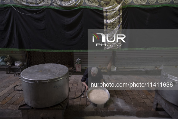 An Iranian man is preparing donated meals during a religious festival to commemorate Tasoua, a day ahead of Ashura, in the Grand Bazaar, in...