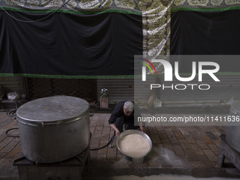 An Iranian man is preparing donated meals during a religious festival to commemorate Tasoua, a day ahead of Ashura, in the Grand Bazaar, in...