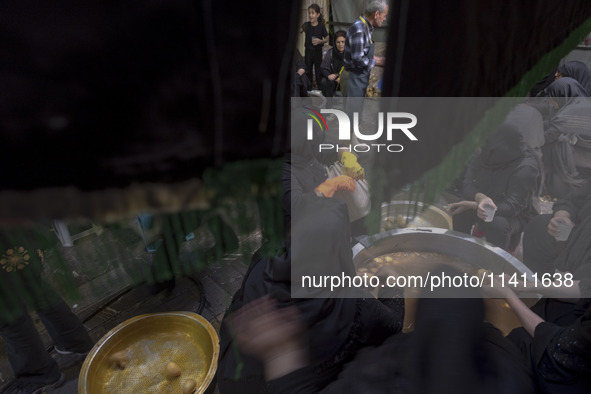 Iranian women are preparing donated meals during a religious festival to commemorate Tasoua, a day ahead of Ashura, in the Grand Bazaar, in...