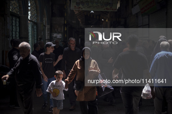 An Iranian woman and her young son are walking along a bazaar while participating in a religious festival to commemorate Tasoua, a day ahead...