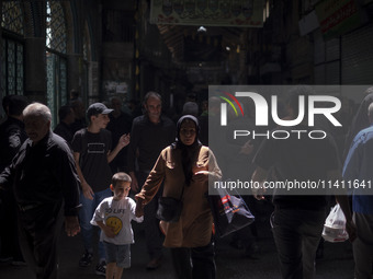 An Iranian woman and her young son are walking along a bazaar while participating in a religious festival to commemorate Tasoua, a day ahead...