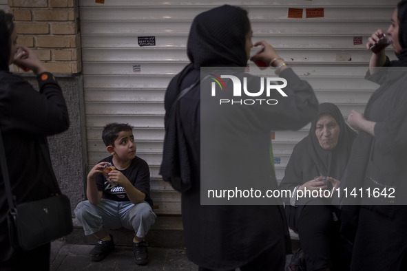 An Iranian family is drinking and eating donated tea and sweets while participating in a religious festival to commemorate Tasoua, a day ahe...