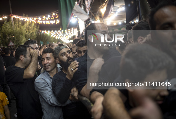 Iranian men are standing in line while waiting to receive donated meals during a religious rally to commemorate Tasoua, in Dolatabad neighbo...