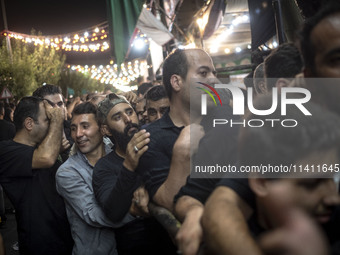 Iranian men are standing in line while waiting to receive donated meals during a religious rally to commemorate Tasoua, in Dolatabad neighbo...