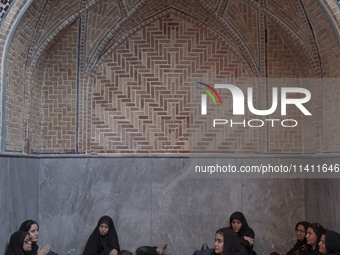 A group of young Iranian women are sitting together at a mosque during a religious festival to commemorate Tasoua, a day ahead of Ashura, in...