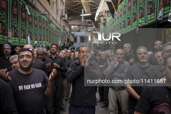 An Iranian man is mourning while participating in a religious festival to commemorate Tasoua, a day ahead of Ashura, in the Grand Bazaar, in...