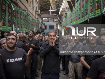 An Iranian man is mourning while participating in a religious festival to commemorate Tasoua, a day ahead of Ashura, in the Grand Bazaar, in...