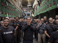 An Iranian man is mourning while participating in a religious festival to commemorate Tasoua, a day ahead of Ashura, in the Grand Bazaar, in...