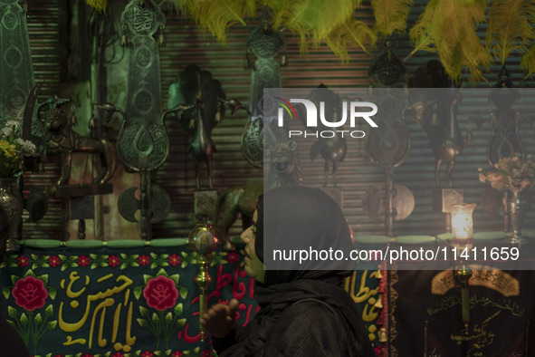 A young Iranian woman is beating herself while standing next to a religious symbol during a religious festival to commemorate Tasoua, a day...