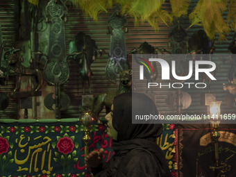 A young Iranian woman is beating herself while standing next to a religious symbol during a religious festival to commemorate Tasoua, a day...