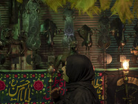 A young Iranian woman is beating herself while standing next to a religious symbol during a religious festival to commemorate Tasoua, a day...