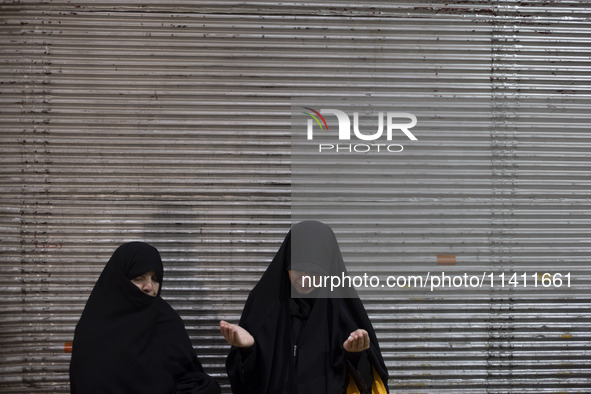 Two veiled women are praying while participating in a religious festival to commemorate Tasoua, a day ahead of Ashura, in the Grand Bazaar,...