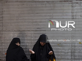 Two veiled women are praying while participating in a religious festival to commemorate Tasoua, a day ahead of Ashura, in the Grand Bazaar,...