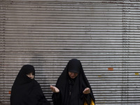 Two veiled women are praying while participating in a religious festival to commemorate Tasoua, a day ahead of Ashura, in the Grand Bazaar,...