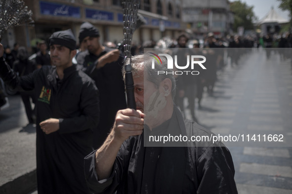 An Iranian mourner is beating himself with a chain during a religious festival to commemorate Tasoua, a day ahead of Ashura, in the Grand Ba...