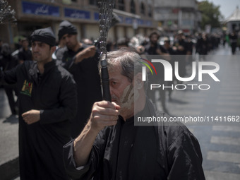 An Iranian mourner is beating himself with a chain during a religious festival to commemorate Tasoua, a day ahead of Ashura, in the Grand Ba...