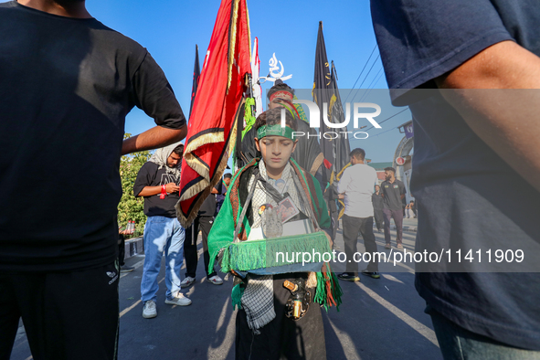 A Kashmiri Shia Muslim boy is walking in a procession on the 8th of Muharram in Srinagar, Indian Administered Kashmir, on July 15, 2024. 