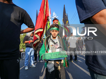 A Kashmiri Shia Muslim boy is walking in a procession on the 8th of Muharram in Srinagar, Indian Administered Kashmir, on July 15, 2024. (