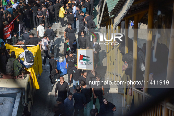 Kashmiri Shia Muslims are displaying a placard in solidarity with Palestine during a procession on the 8th of Muharram in Srinagar, Indian A...