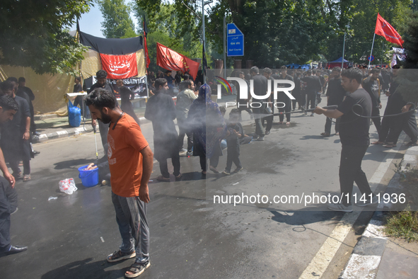 A Kashmiri Shia Muslim is spraying water on the people during a Muharram procession on the 8th of Muharram in Srinagar, Indian Administered...