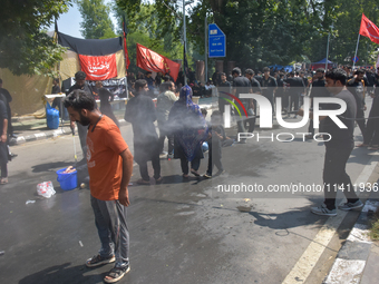 A Kashmiri Shia Muslim is spraying water on the people during a Muharram procession on the 8th of Muharram in Srinagar, Indian Administered...