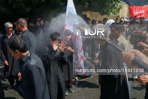 A Kashmiri Shia Muslim is spraying water on the people during a Muharram procession on the 8th of Muharram in Srinagar, Indian Administered...