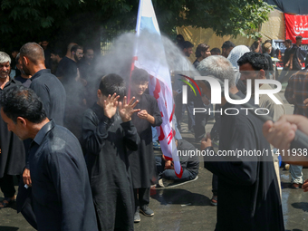 A Kashmiri Shia Muslim is spraying water on the people during a Muharram procession on the 8th of Muharram in Srinagar, Indian Administered...