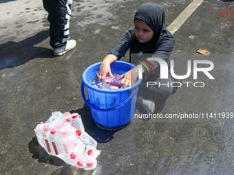 A Kashmiri Shia Muslim girl is offering water during a Muharram procession in Srinagar, Indian Administered Kashmir, on July 15, 2024. (