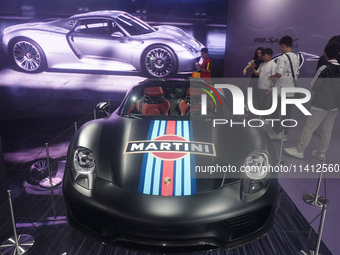 People are looking at Porsche's hybrid supercar ''918 Spyder'' at the West Lake in Hangzhou, China, on July 16, 2024. (