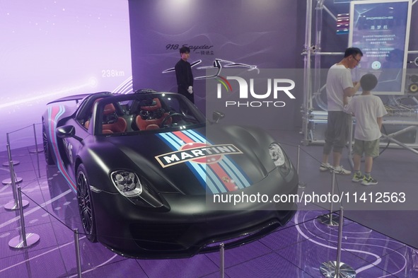 People are looking at Porsche's hybrid supercar ''918 Spyder'' at the West Lake in Hangzhou, China, on July 16, 2024. 