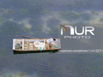 A crab farmer is performing daily management tasks such as increasing oxygen, fetching water, and feeding at a hairy crab ecological breedin...