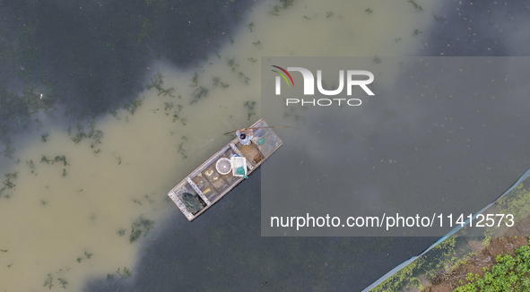 A crab farmer is performing daily management tasks such as increasing oxygen, fetching water, and feeding at a hairy crab ecological breedin...