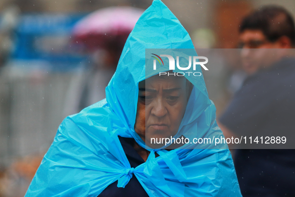 A person is covering himself from the rain with a raincoat while walking in downtown Mexico City, Mexico, on July 10, 2024. 