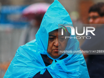 A person is covering himself from the rain with a raincoat while walking in downtown Mexico City, Mexico, on July 10, 2024. (