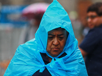 A person is covering himself from the rain with a raincoat while walking in downtown Mexico City, Mexico, on July 10, 2024. (