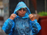 A person is covering herself from the rain with a raincoat while walking in downtown Mexico City, Mexico, on July 10, 2024. (