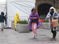 A person is covering herself from the rain with a raincoat while walking in downtown Mexico City, Mexico, on July 10, 2024. (