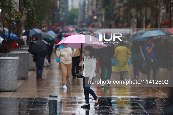 A person is covering herself from the rain with an umbrella while walking through downtown in Mexico City, Mexico, on July 10, 2024. 