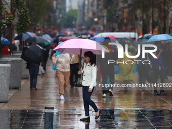 A person is covering herself from the rain with an umbrella while walking through downtown in Mexico City, Mexico, on July 10, 2024. (