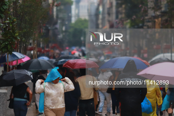 People are covering themselves from the rain with umbrellas while walking through downtown in Mexico City, Mexico, on July 10, 2024. 