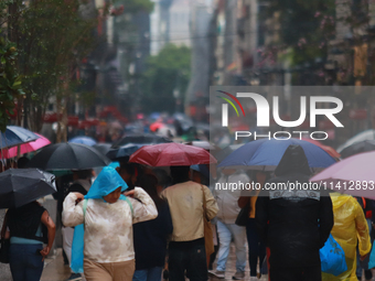 People are covering themselves from the rain with umbrellas while walking through downtown in Mexico City, Mexico, on July 10, 2024. (