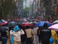 People are covering themselves from the rain with umbrellas while walking through downtown in Mexico City, Mexico, on July 10, 2024. (