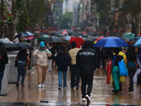 People are covering themselves from the rain with umbrellas while walking through downtown in Mexico City, Mexico, on July 10, 2024. (