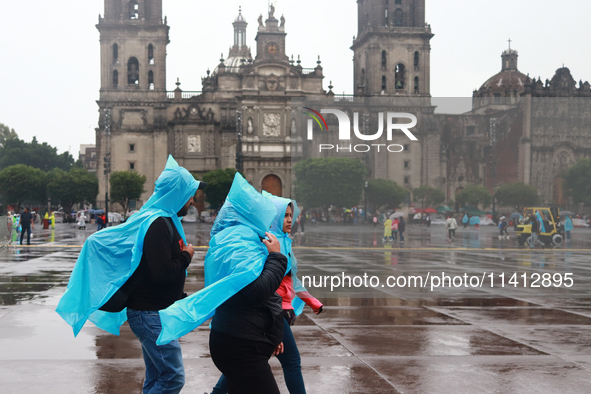 People are covering themselves from the rain with raincoats while walking through downtown in Mexico City, Mexico, on July 10, 2024. 