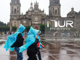 People are covering themselves from the rain with raincoats while walking through downtown in Mexico City, Mexico, on July 10, 2024. (