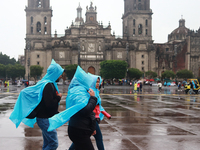 People are covering themselves from the rain with raincoats while walking through downtown in Mexico City, Mexico, on July 10, 2024. (