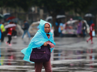 A person is covering herself from the rain with a raincoat while walking in downtown Mexico City, Mexico, on July 10, 2024. (