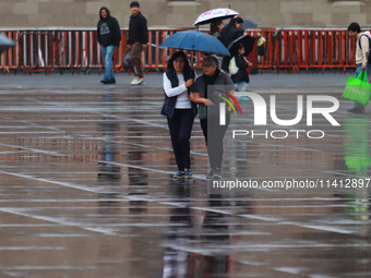 People are covering themselves from the rain with umbrellas while walking through downtown in Mexico City, Mexico, on July 10, 2024. (