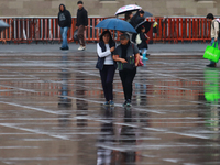 People are covering themselves from the rain with umbrellas while walking through downtown in Mexico City, Mexico, on July 10, 2024. (